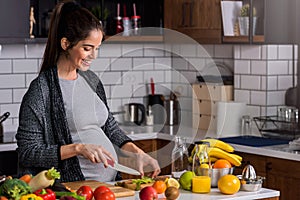 Young pregnant woman preparing healthy food with fruit and vegetables