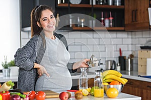 Pregnant woman preparing healthy food with lots of fruit and vegetables at home