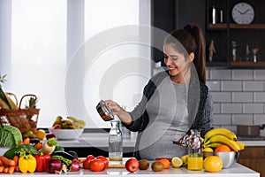 Young pregnant woman preparing healthy food with fruit and vegetables