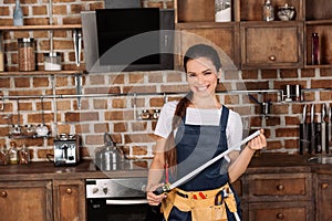 beautiful smiling young repairwoman with measuring tape standing at kitchen and looking