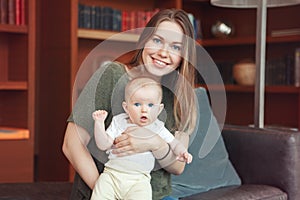 Beautiful smiling young white Caucasian woman mother holding cute adorable baby boy girl child