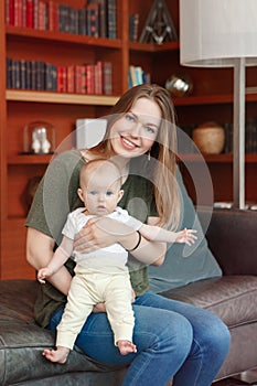 Beautiful smiling young white Caucasian woman mother holding cute adorable baby boy girl child