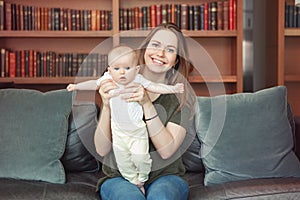 Beautiful smiling young white Caucasian woman mother holding cute adorable baby boy girl child