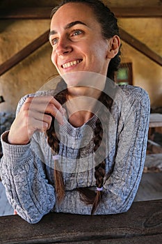 Beautiful smiling young woman braided hair in summer beer restaurant bar at old wooden table