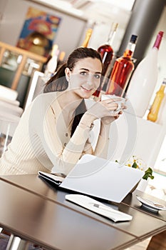 Beautiful smiling young woman drinking a cup of coffee at the cafe coffee bar, ice cream shop and pastry shop. Student girl with
