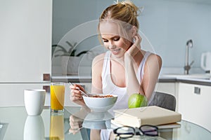 beautiful smiling young woman eating muesli for breakfast