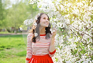 Beautiful smiling young woman enjoying smell flowering spring