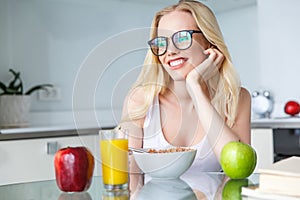 beautiful smiling young woman in eyeglasses eating breakfast