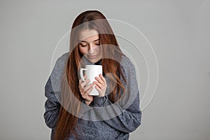 Beautiful smiling young woman feeling cold and drinking hot tea