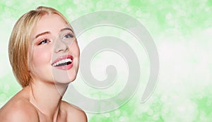 Beautiful smiling young woman girl face with great white teeth and clean skin on a blur green background