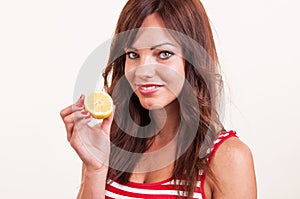 Beautiful smiling young woman holding half lemon