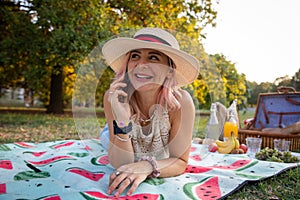 Beautiful smiling young woman during picnic enjoys making phone calls