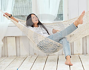 Beautiful smiling young woman relaxing in hammock at home