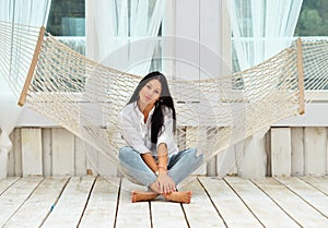 Beautiful smiling young woman relaxing in hammock at home