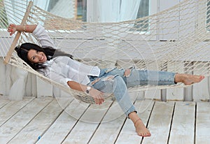 Beautiful smiling young woman relaxing in hammock at home