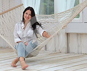 Beautiful smiling young woman relaxing in hammock at home