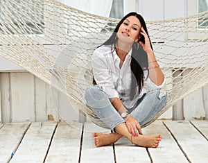 Beautiful smiling young woman relaxing in hammock at home