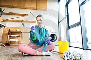 beautiful smiling young woman in rubber gloves holding plastic bottles with cleaning