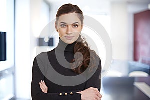 Beautiful smiling young woman standing in the office and looking at camera