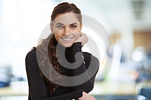 Beautiful smiling young woman standing in the office and looking at camera