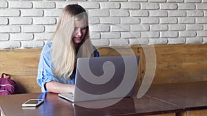 Beautiful smiling young woman using her laptop at the cafe.