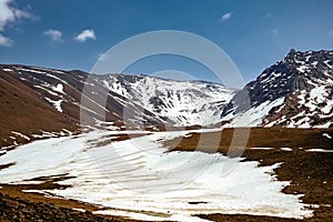 Beautiful snow covered rocky mountains with stormclouds on background