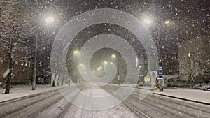 Beautiful snow falls in clusters and falls non-stop. The entire street and roadway are covered with snow.