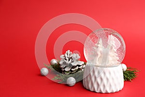 Beautiful snow globe and Christmas decor on red background, space for text