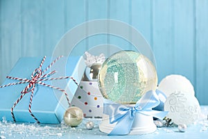 Beautiful snow globe, gift box and Christmas decor on light blue table