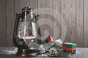 Beautiful snow globe in vintage lantern, gifts and Christmas decor on grey wooden table. Space for text