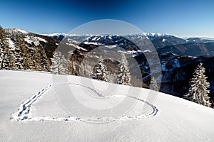 Beautiful snowy country in winter mountains. Heart shape in snow