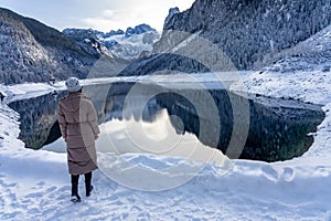 Beautiful snowy winter landscape with Dachstein mountain and Gosausee in Austria near Hallstatt with tourist woman