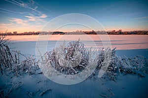 Beautiful snowy winter landscape. Winter golden sunrise on the frozen river. Golden light on snow. Russia, Siberia.