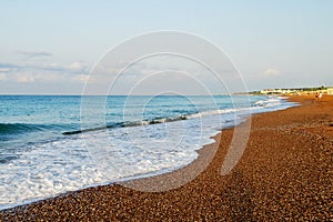 Beautiful soft sea wave on the beach with small pebbles and sand.