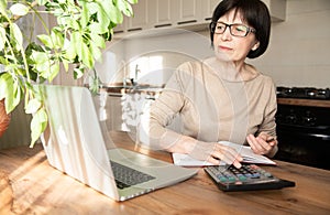 A beautiful sophisticated elderly woman talking on video communication, working at home with a laptop and doing