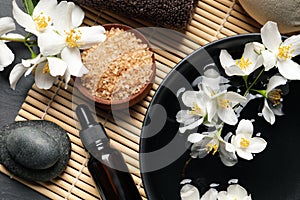 Beautiful spa composition with jasmine essential oil and fresh flowers on table, flat lay