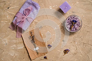 Purple sea salt, a wooden comb towel on a concrete brown background.