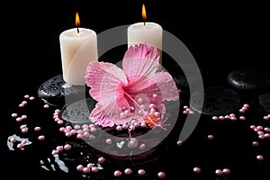 Beautiful spa setting of pink hibiscus, candles, zen stones