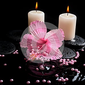 Beautiful spa setting of pink hibiscus, candles, zen stones