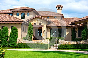 Beautiful Spanish style house exterior with natural rock facing and veneer siding