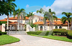 Beautiful Spanish style luxury mansion residential home with a privacy gate and palm trees