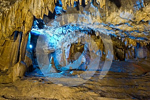 Beautiful speleothem stalagnata, stalactites, stalagmites in natural cave illuminated by color lights