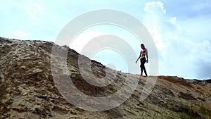 Beautiful sport girl walks on top of a hill