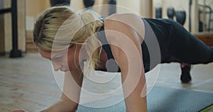 Beautiful sport woman doing plank workout at a gym to improve her abs. Fitness girl fit workout in gym working her core