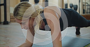 Beautiful sport woman doing plank workout at a gym to improve her abs. Fitness girl fit workout in gym working her core