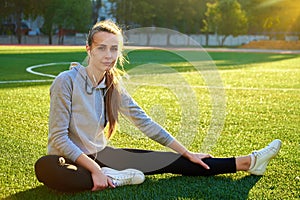 Beautiful sport woman doing stretching fitness exercise in city park at green grass. Yoga postures