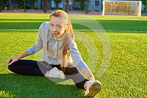 Beautiful sport woman doing stretching fitness exercise in city park at green grass. Yoga postures