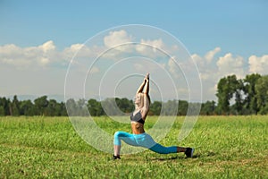 Beautiful sport woman doing stretching fitness exercise in city park at green grass.