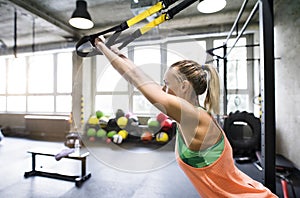 Beautiful sport woman doing suspension training, total resistance exercise. Routine workout for woman& x27;s physical and