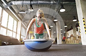 Beautiful sport woman exercising on balance ball in gym, performing pushups. Routine workout for woman& x27;s physical